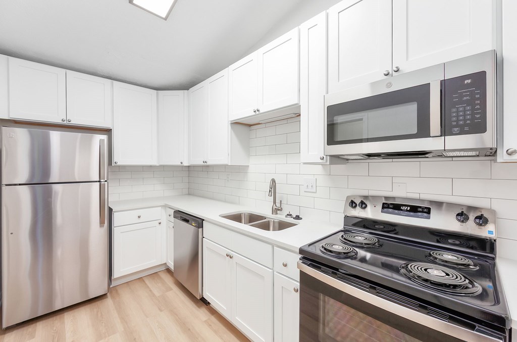 A kitchen with a stove, refrigerator, and microwave.
