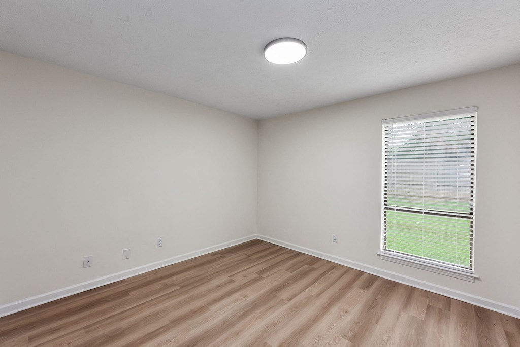 A room with a window and wooden flooring.