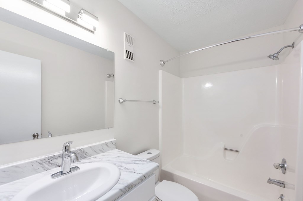 A white bathroom with a sink, toilet, and bathtub.