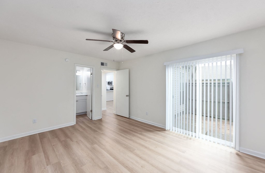 A room with a ceiling fan and wooden flooring.
