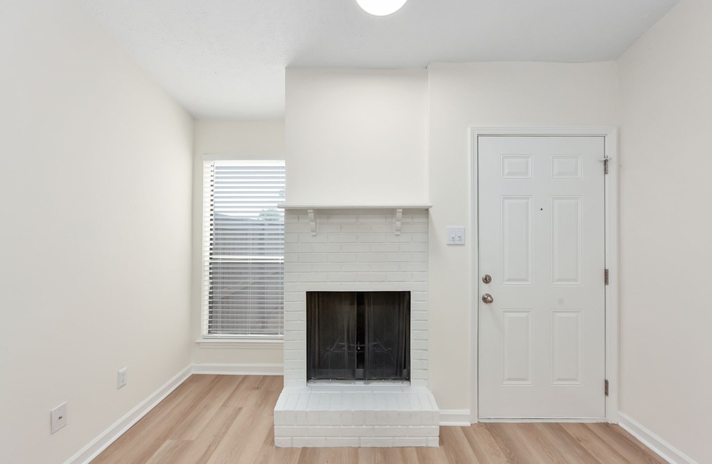 A white fireplace in a room with a door and a window.