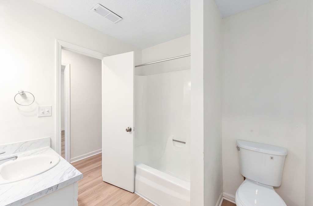 A white bathroom with a toilet, sink, and bathtub.