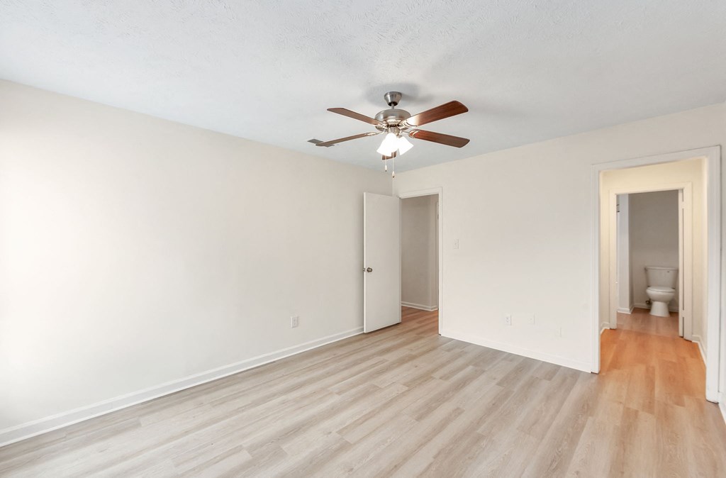 A room with a ceiling fan and wooden flooring.