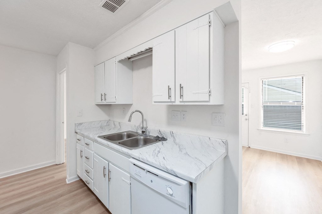 A kitchen with white cabinets and a marble countertop.