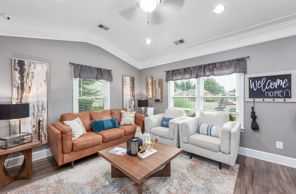 A living room with a brown couch, a white chair, and a wooden coffee table.