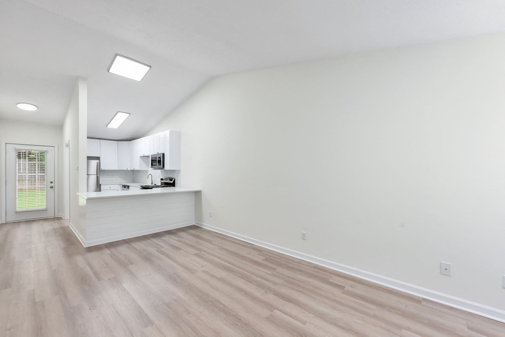 A room with a white wall and wooden floor.