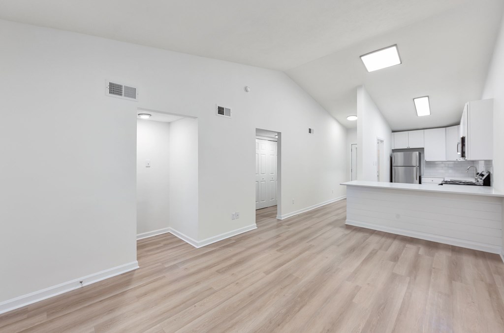 A spacious room with wooden flooring and white walls.