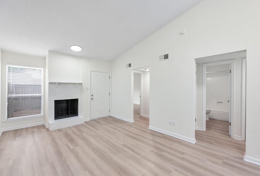 A spacious living room with a fireplace and hardwood floors.