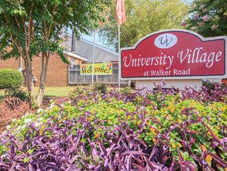 the sign for university village at walker road in front of a garden