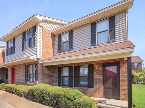 the front of a brick apartment building with a sidewalk
