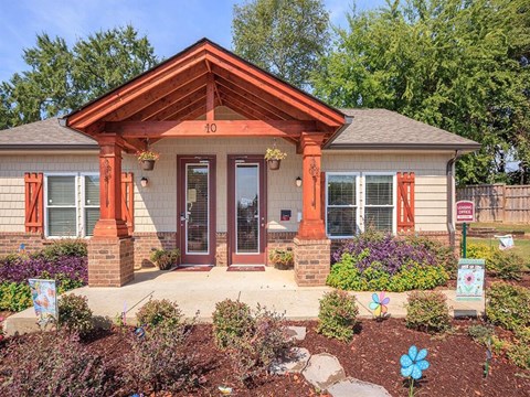 the front of a house with a porch and a flower garden