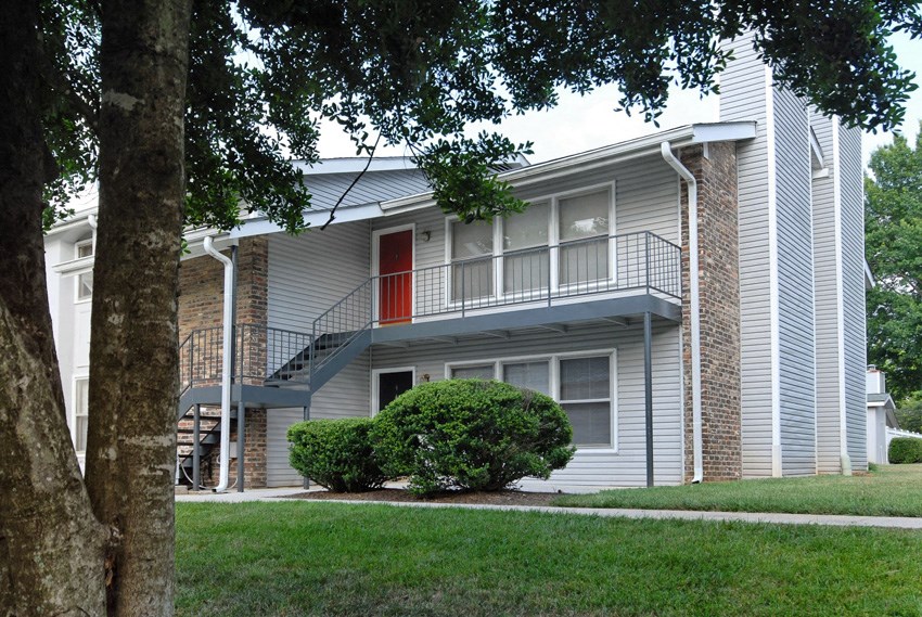 the exterior of an apartment building with stairs and a red door