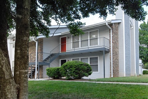 the exterior of an apartment building with stairs and a red door