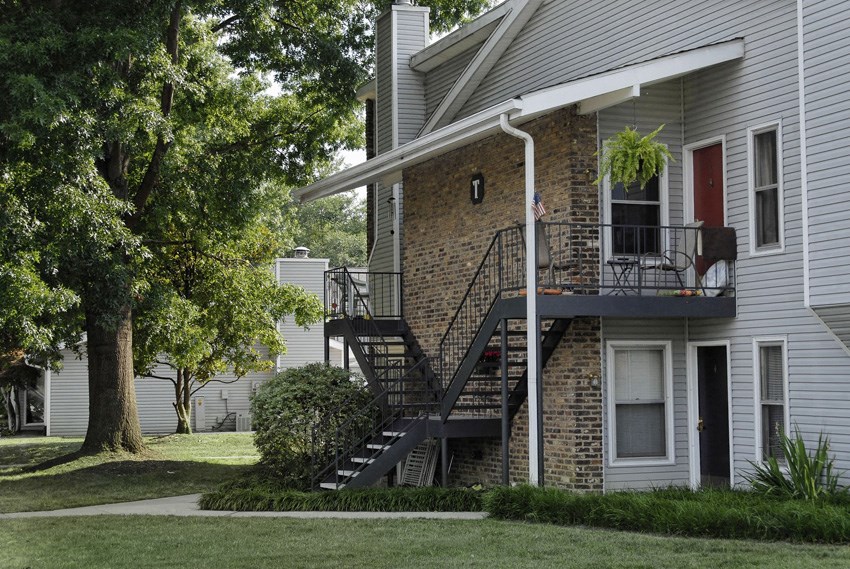 the exterior of an apartment building with stairs and a balcony