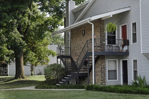 the exterior of an apartment building with stairs and a balcony