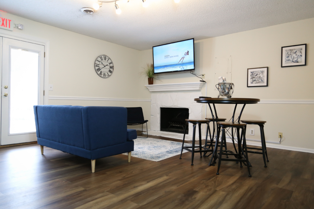 a living room with a couch and stools and a tv on the wall