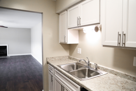 an empty kitchen with white cabinets and a sink