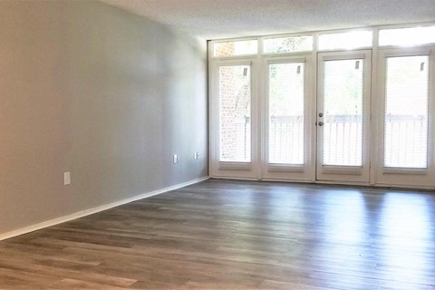 an empty living room with a hard wood floor and doors