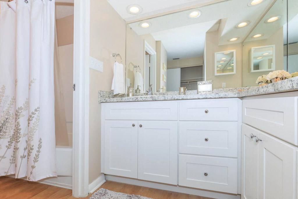 a white bathroom with a large mirror and a counter top