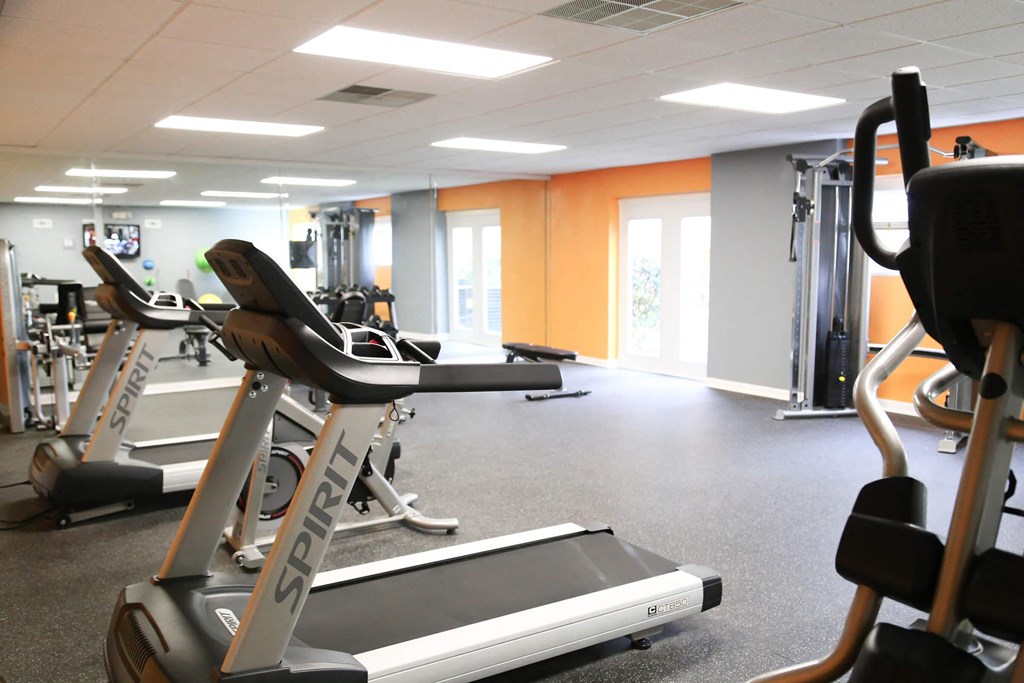 a gym with cardio equipment and weights on the floor