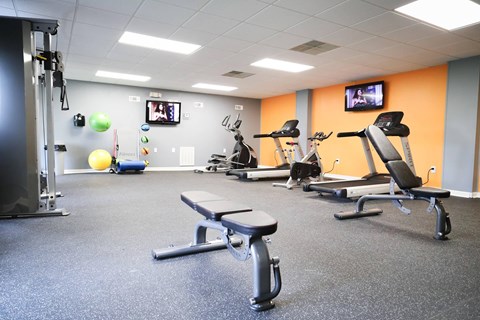 a gym with treadmills and other exercise equipment and a tv
