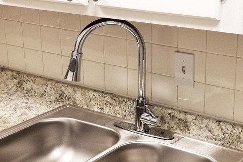 a kitchen sink with a chrome faucet over it