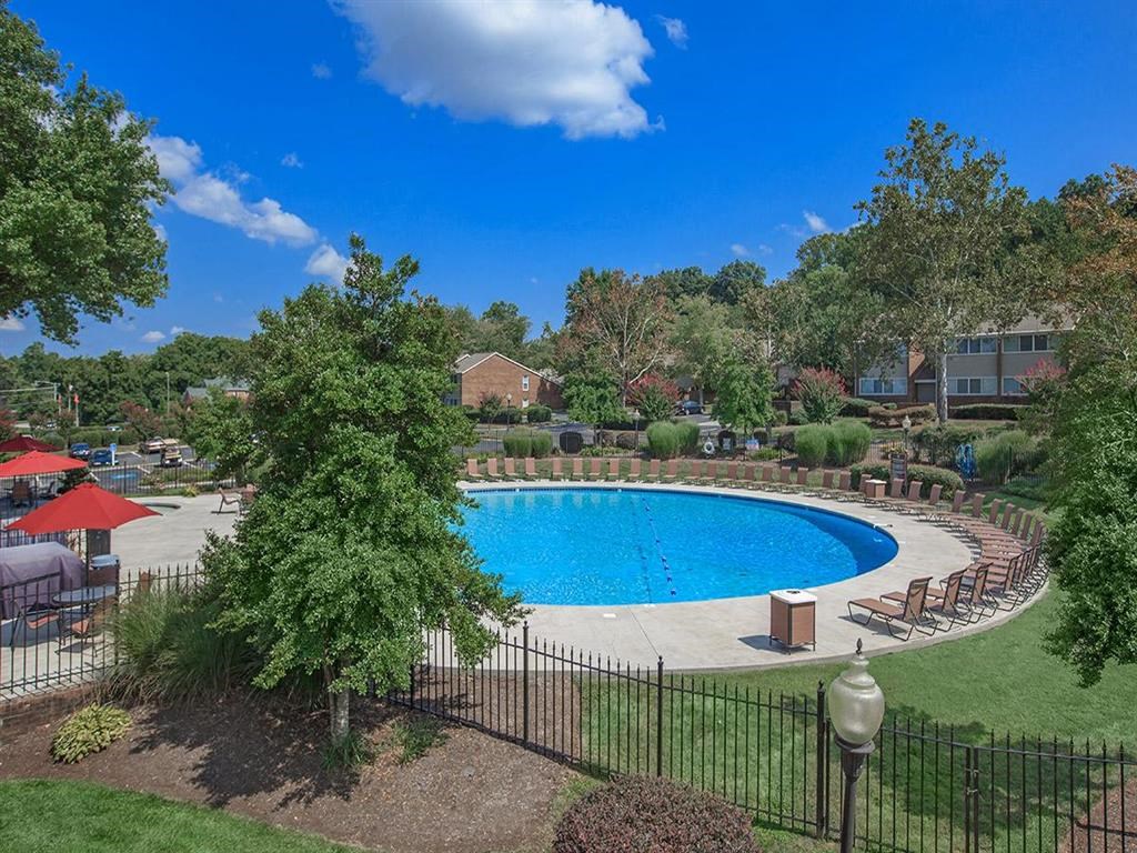 a swimming pool with trees and chairs around it
