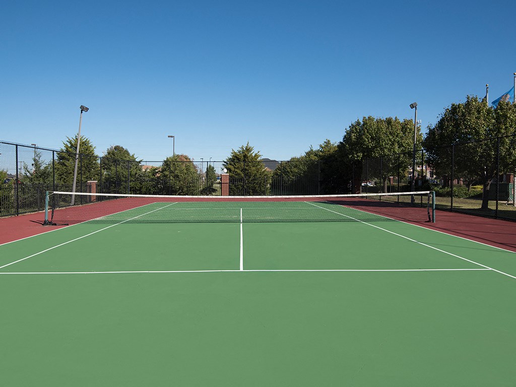a tennis court with trees in the background and a blue sky