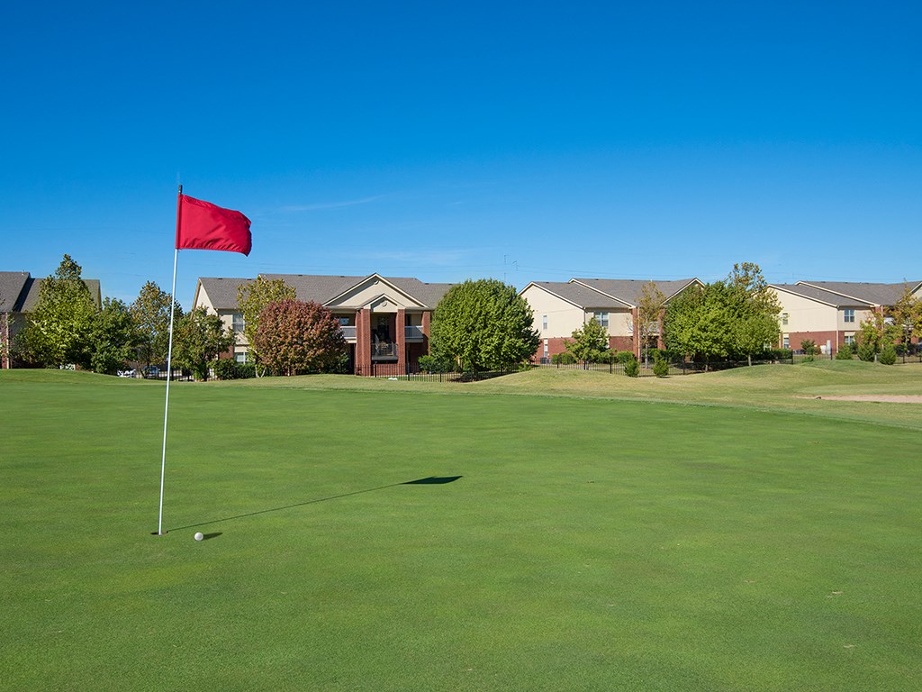 a red flag on a golf course with houses in the background