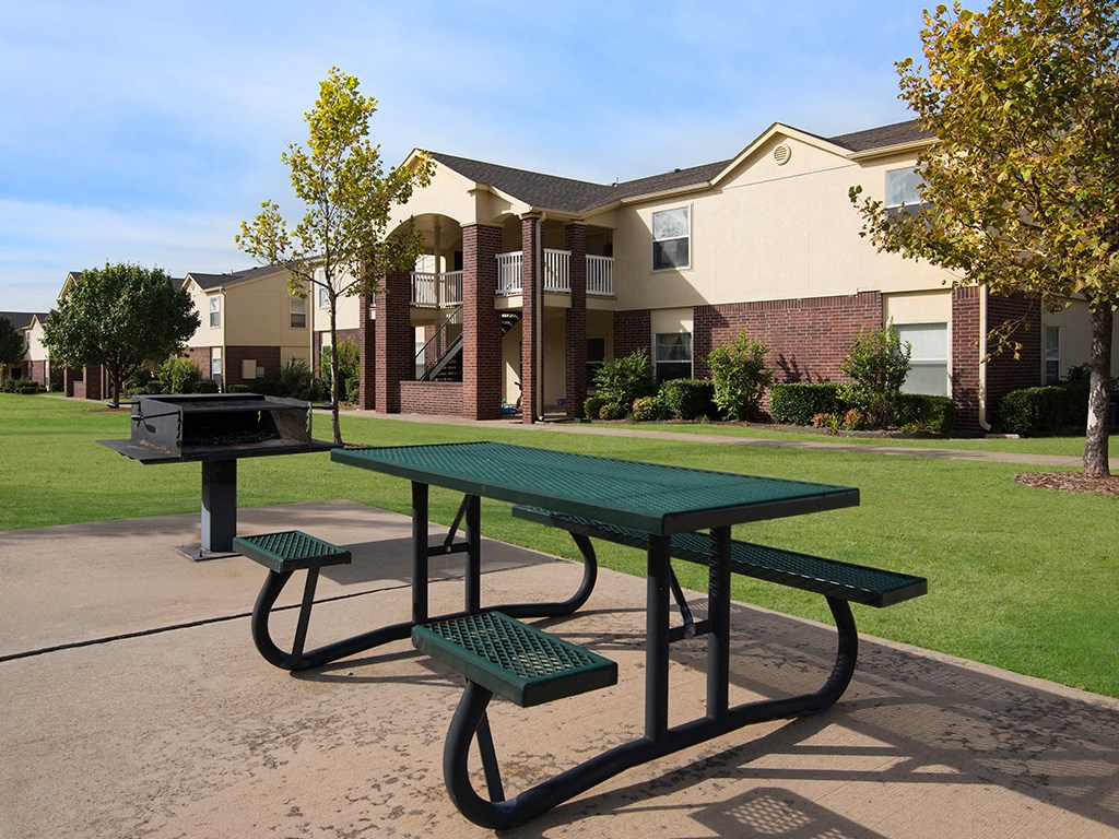 a picnic table with a grill in front of an apartment building