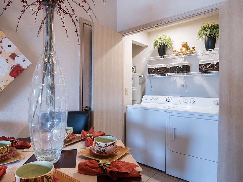 a kitchen with a washing machine and a table with tea cups and a vase