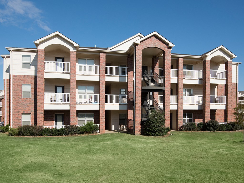 an exterior view of an apartment building with a green yard