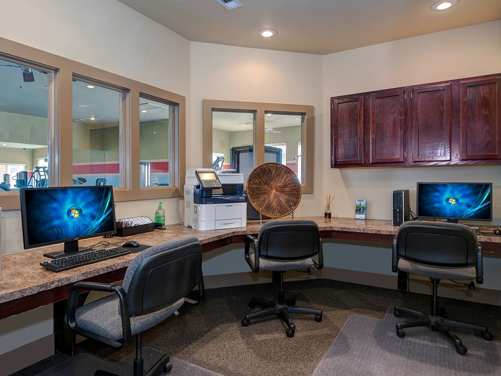 two desks with computers and three chairs in a room