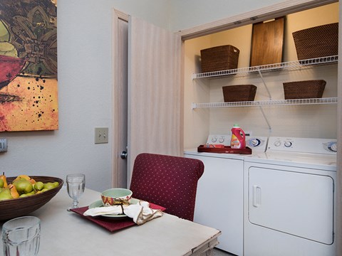 a laundry room with a washing machine and a table with a chair and a bowl