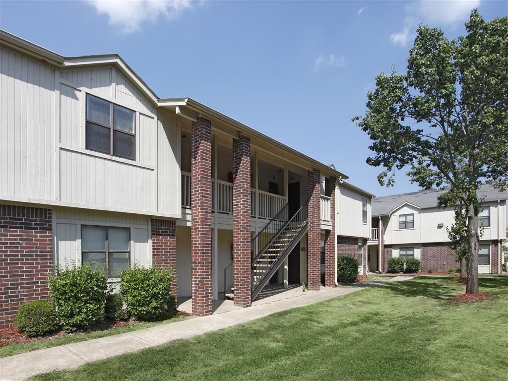 the outlook of an apartment building with a lawn and trees