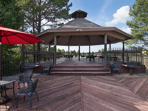 a gazebo with tables and chairs on a wooden deck