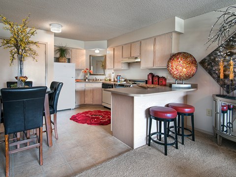 a kitchen with a bar and stools and a living room with a dining area