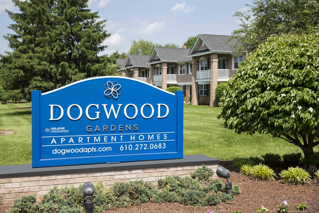 a sign for dogwood gardens apartment homes in front of a yard with a house