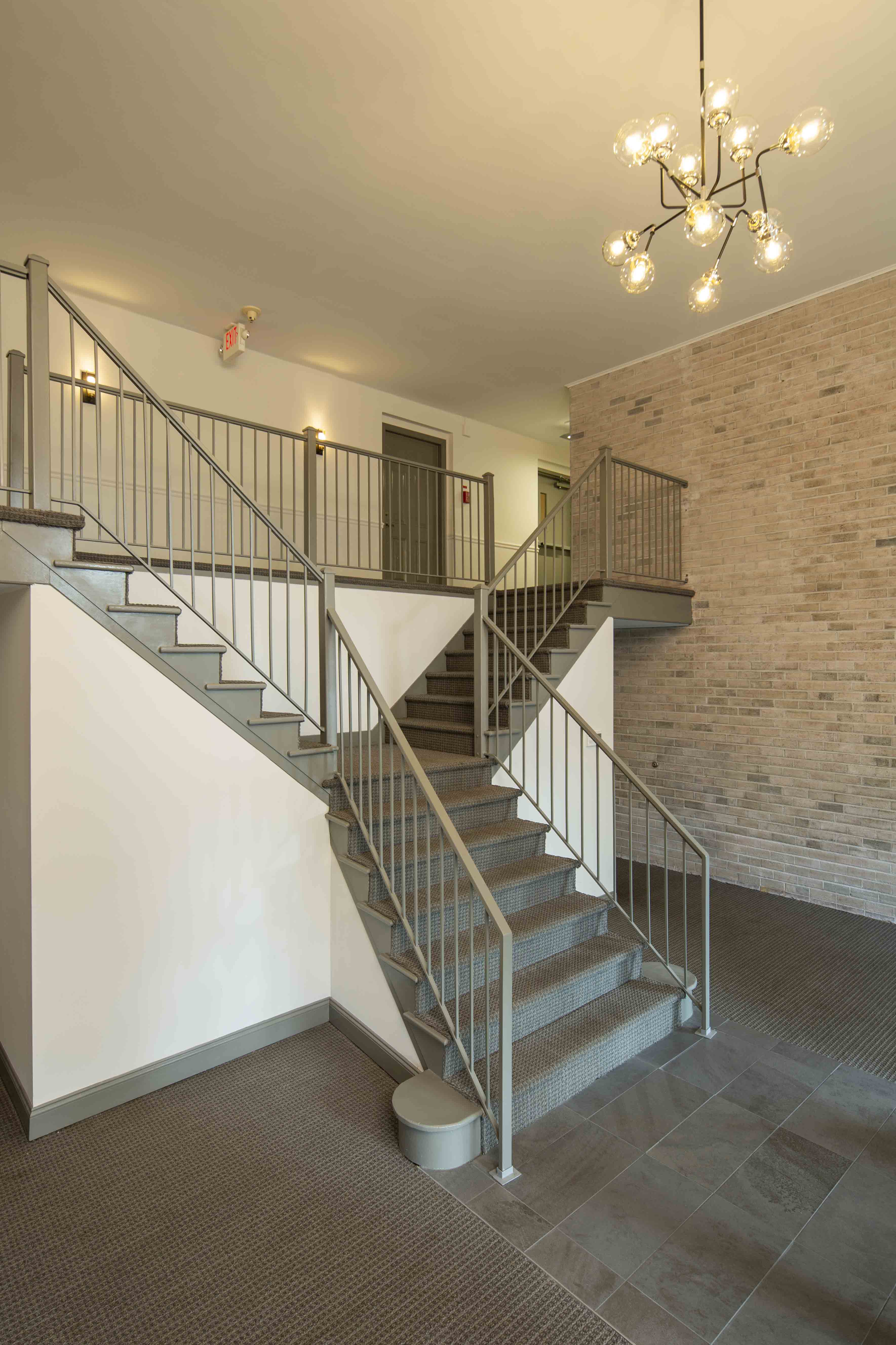 a staircase in a building with a brick wall and metal railings