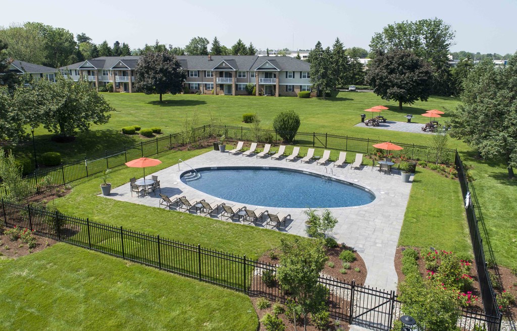 an aerial view of a pool and lawn with umbrellas