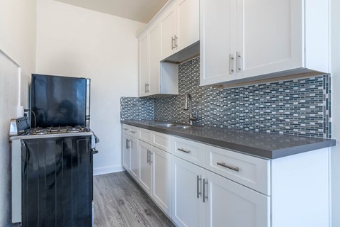 a kitchen with white cabinets and a counter top and a stove
