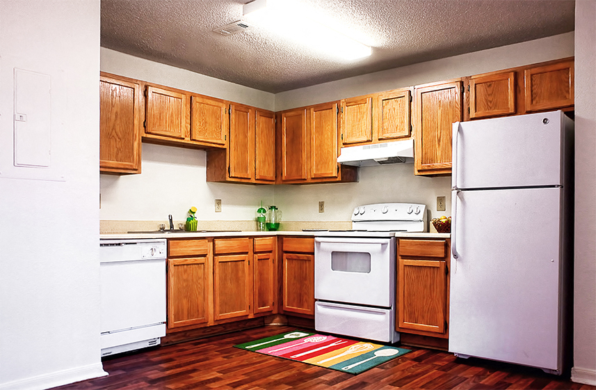 an empty kitchen with white appliances and wooden cabinets
