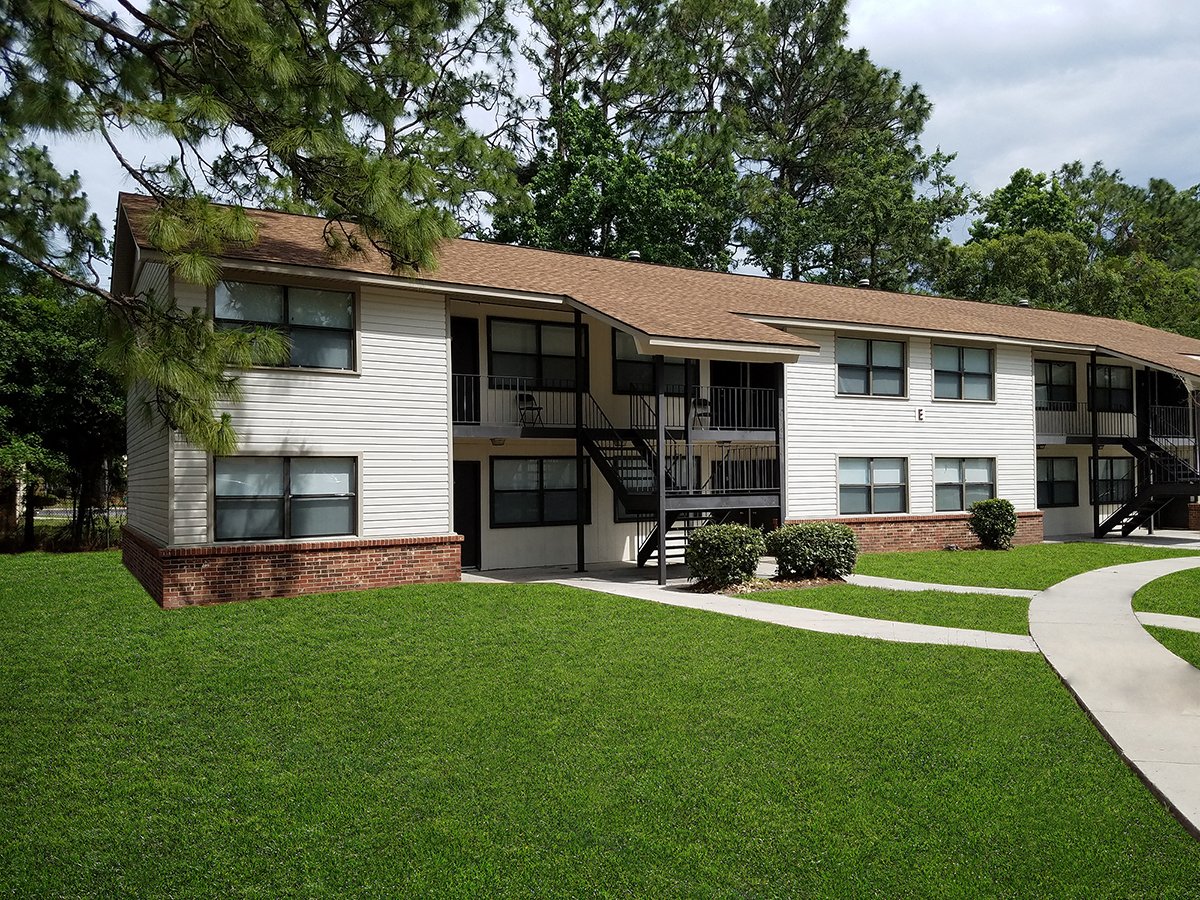 A white building with a brown roof and a green lawn in front.