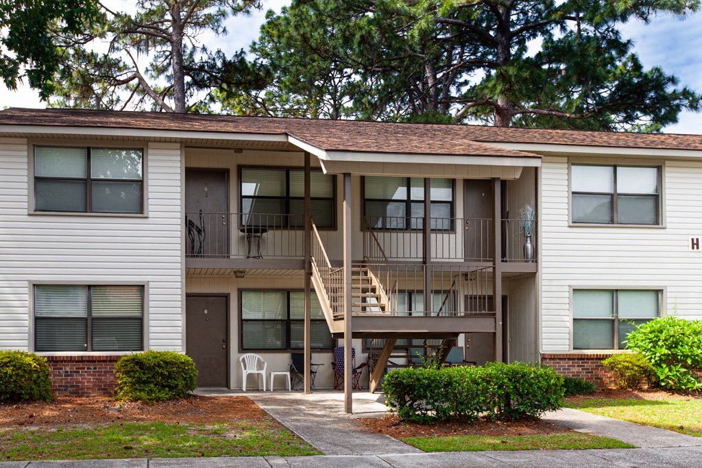 A two-story apartment building with a balcony and a staircase.