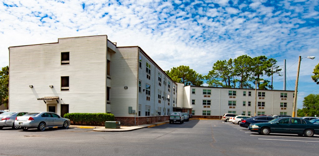 A parking lot with cars and apartment buildings.