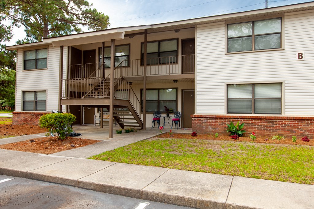 Apartment building with a balcony and a small garden in front.