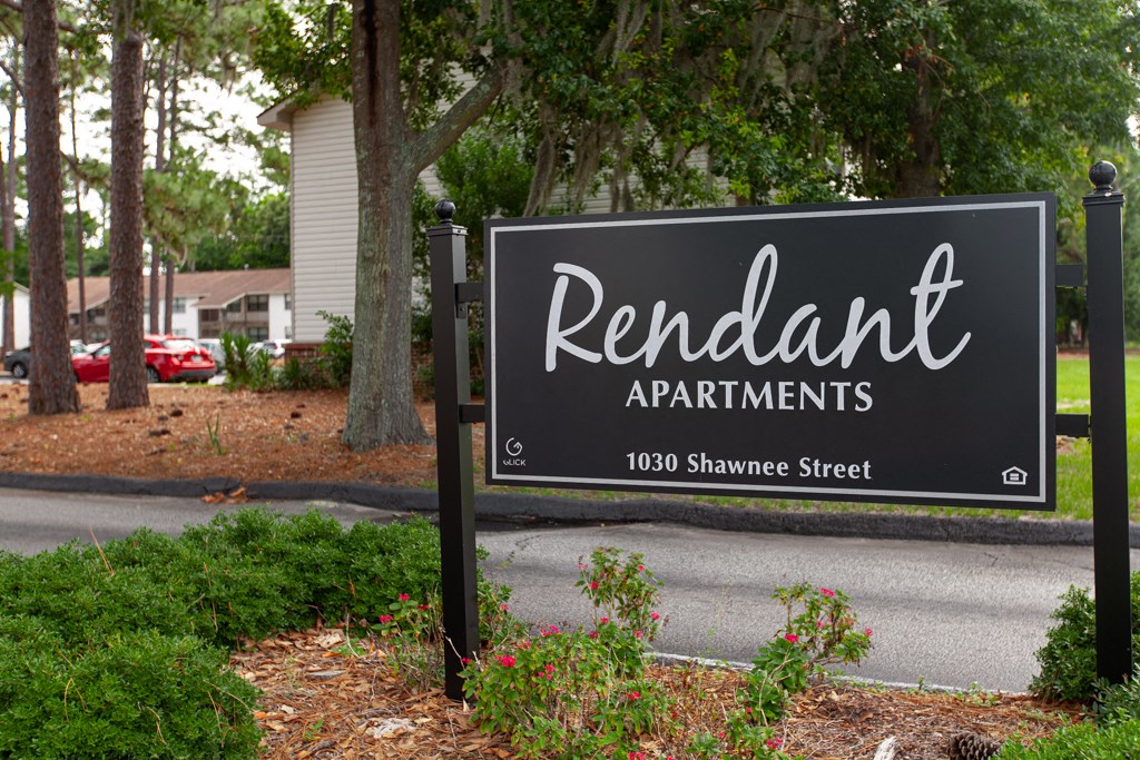 A sign for Rendant Apartments is displayed in front of a tree.