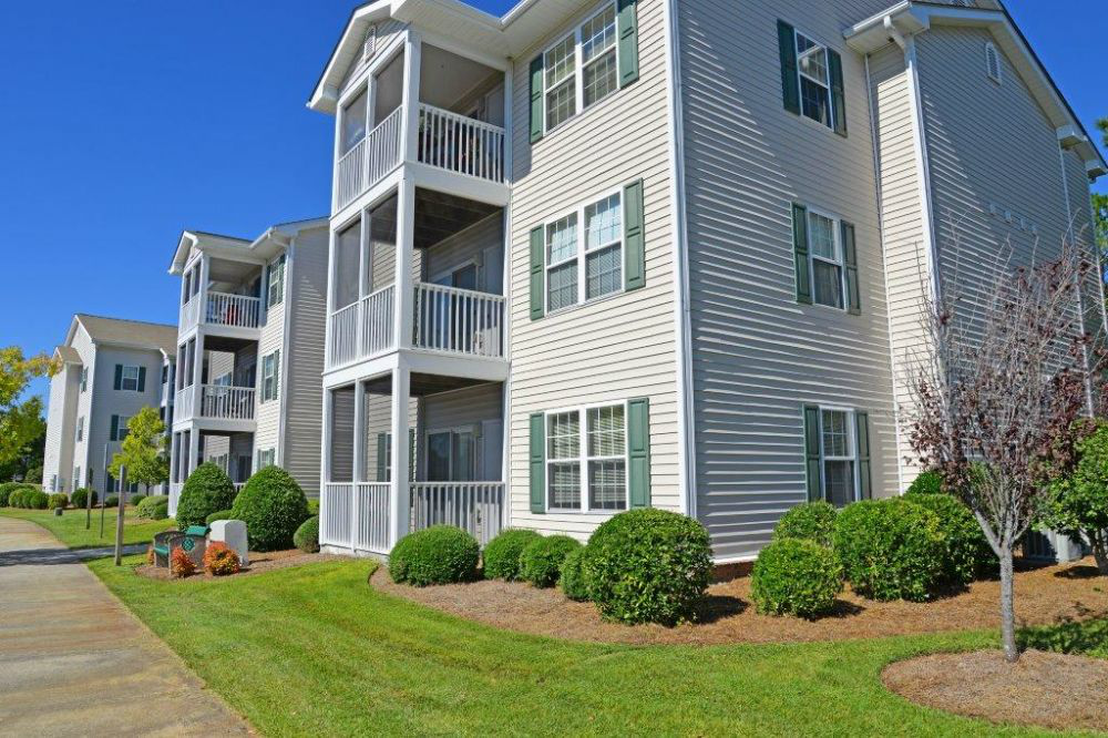 an apartment building with a sidewalk and green grass