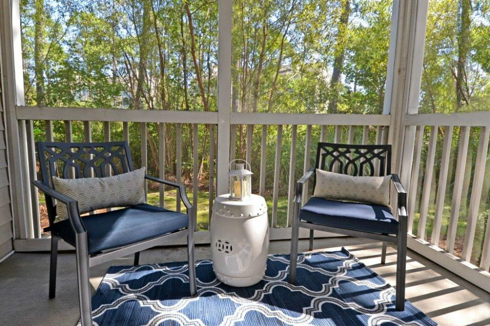 a porch with two chairs and a table with a gas bottle on it