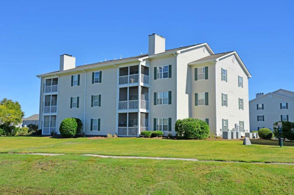 a large apartment building with a green lawn